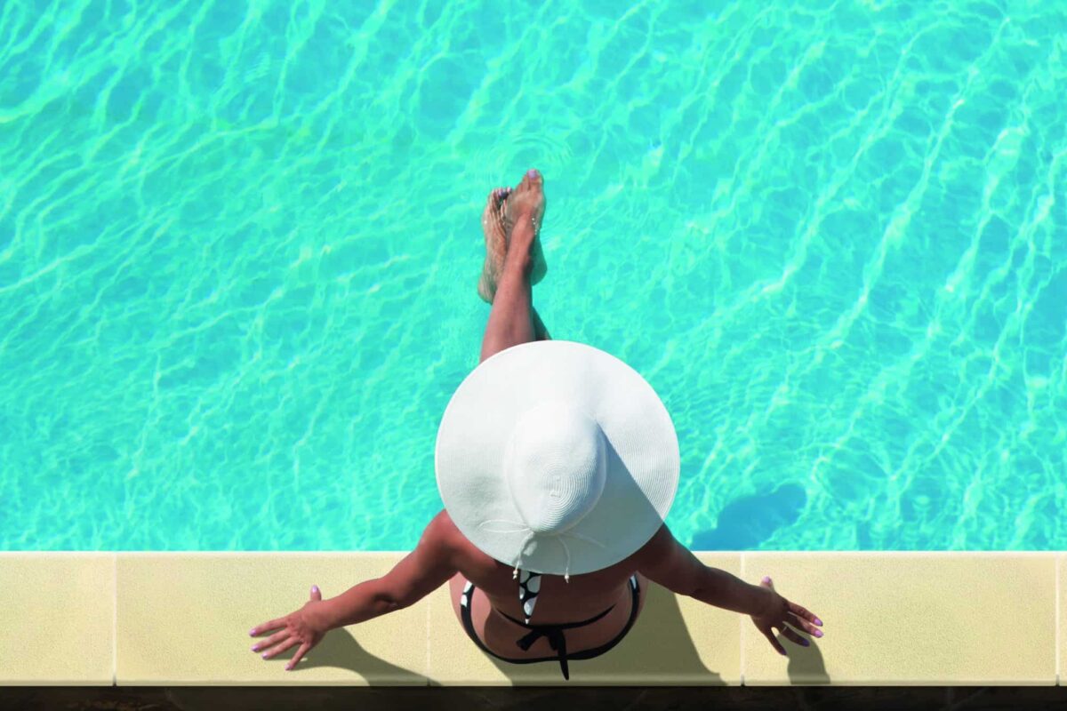 Young woman sitting on the ledge of the pool.